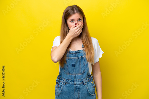 Young caucasian woman isolated on yellow background covering mouth with hand