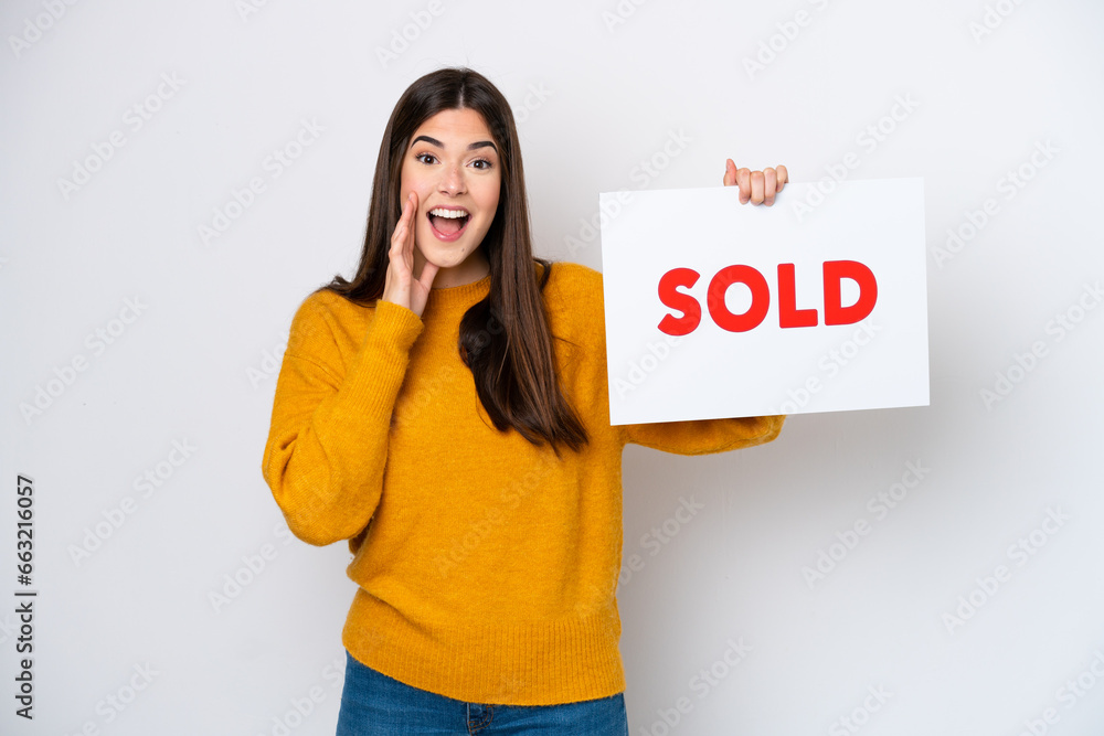 Young Brazilian woman isolated on white background holding a placard with text SOLD and shouting Young Brazilian woman isolated on white background holding a placard with text SOLD and shouting