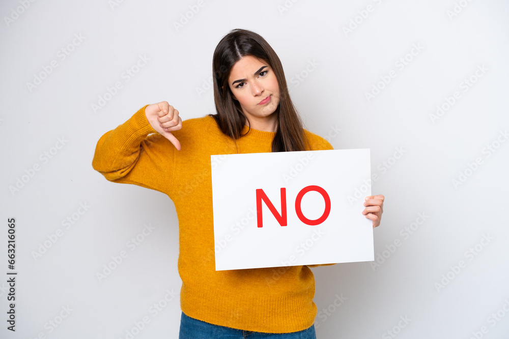 Young Brazilian woman isolated on white background holding a placard with text NO Young Brazilian woman isolated on white background holding a placard with text NO