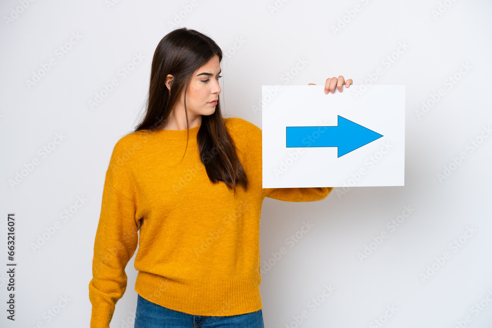Young Brazilian woman isolated on white background holding a placard with arrow symbol Young Brazilian woman isolated on white background holding a placard with arrow symbol