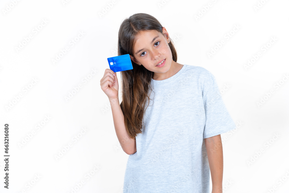Close up photo of optimistic Beautiful little kid girl wearing blue T-shirt hold card Close up photo of optimistic Beautiful little kid girl wearing blue T-shirt hold card
