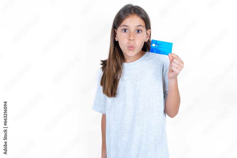 Photo of Beautiful little kid girl wearing blue T-shirt amazed shocked hold credit card payment Photo of Beautiful little kid girl wearing blue T-shirt amazed shocked hold credit card payment