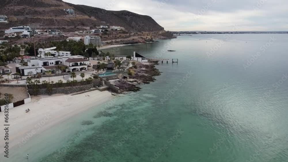 Ascending aerial shot of the wonderful beach of Playa El Caymancito near La paz Baja California Sur Mexico overlooking the turquoise sea and the beautiful buildings during a great vacation Ascending aerial shot of the wonderful beach of Playa El Caymancito near La paz Baja California Sur Mexico overlooking the turquoise sea and the beautiful buildings during a great vacation