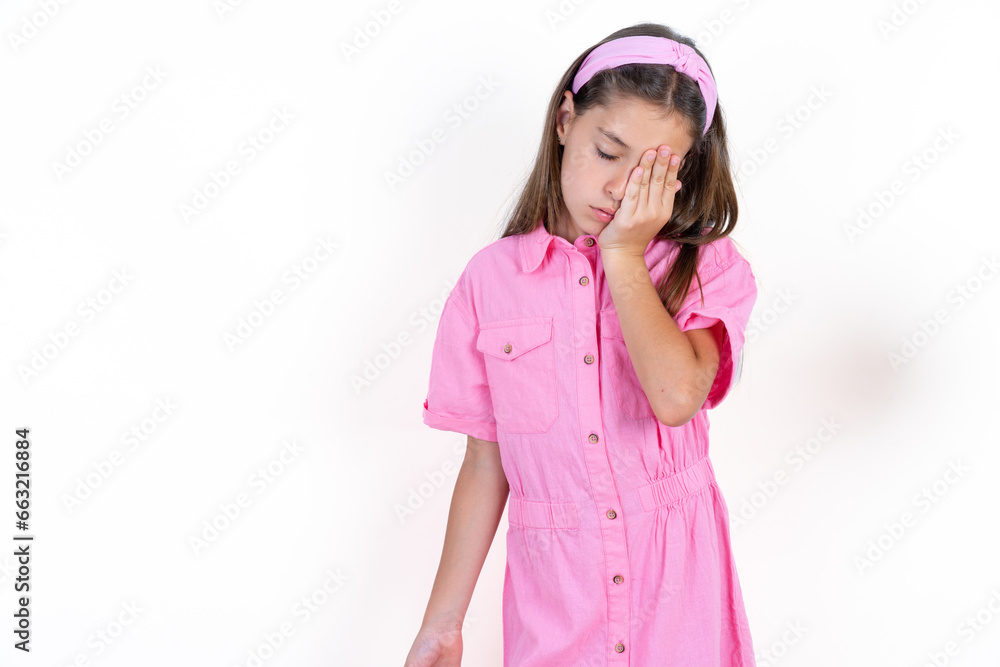 Tired overworked Beautiful little kid girl wearing pink dress has sleepy expression, gloomy look, covers face with hand, has eyes shut, gasps from tiredness, fatigue after party Tired overworked Beautiful little kid girl wearing pink dress has sleepy expression, gloomy look, covers face with hand, has eyes shut, gasps from tiredness, fatigue after party