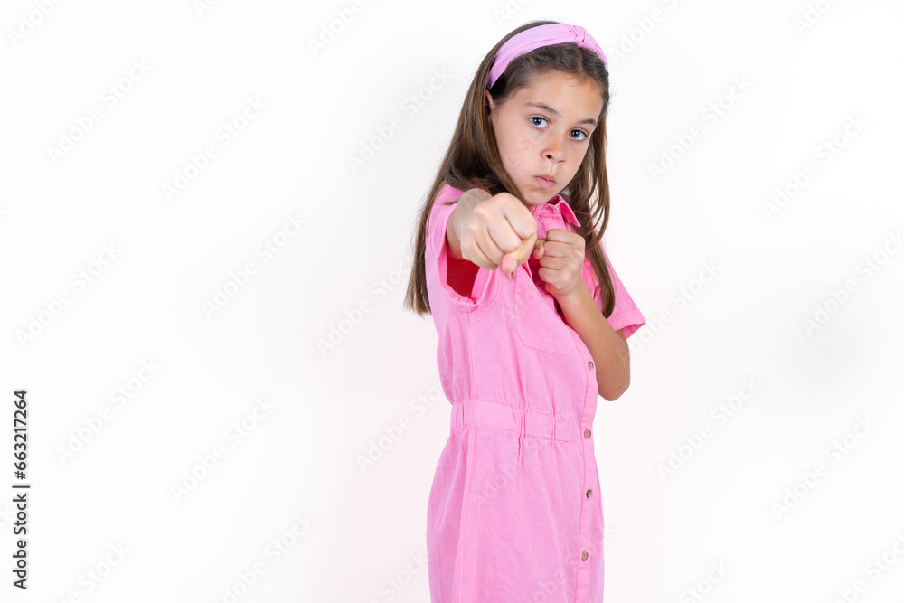 Beautiful little kid girl wearing pink dress Punching fist to fight, aggressive and angry attack, threat and violence Beautiful little kid girl wearing pink dress Punching fist to fight, aggressive and angry attack, threat and violence