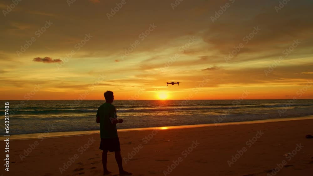 .A man uses a drone to take photos at the beach..Amazing Golden yellow sky during sunset..smooth wave hit on the beach..stunning reflection of colorful cloud in sweet sky on sea surfect.sky texture. .A man uses a drone to take photos at the beach..Amazing Golden yellow sky during sunset..smooth wave hit on the beach..stunning reflection of colorful cloud in sweet sky on sea surfect.sky texture.