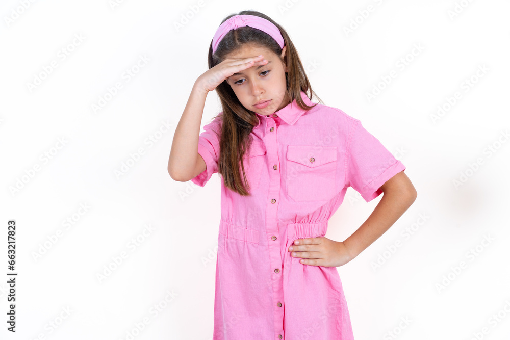 Beautiful little kid girl wearing pink dress having problems, worried and stressed holds hand on forehead. Beautiful little kid girl wearing pink dress having problems, worried and stressed holds hand on forehead.