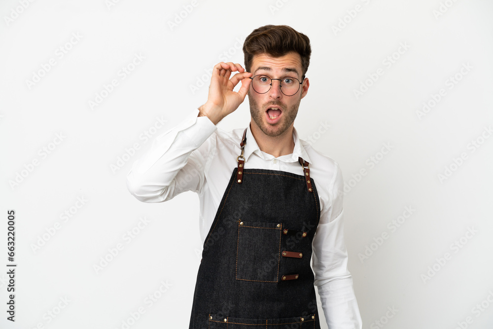 Fototapeta premium Restaurant caucasian waiter isolated on white background with glasses and surprised