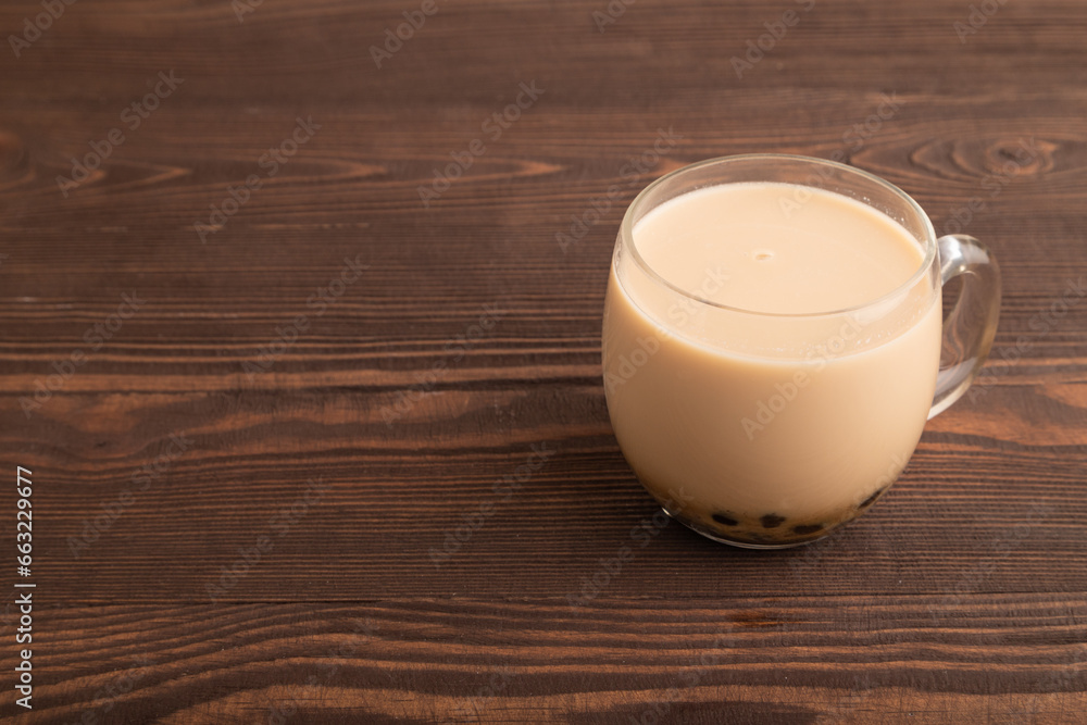 Bubble tea with pistachio and caramel in glass on brown wooden, Side view, copy space. Bubble tea with pistachio and caramel in glass on brown wooden, Side view, copy space.