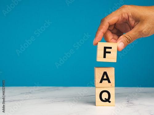 FAQ - frequently asked questions concept. Wooden cubes with words F, A, and Q on a table with a blue background.