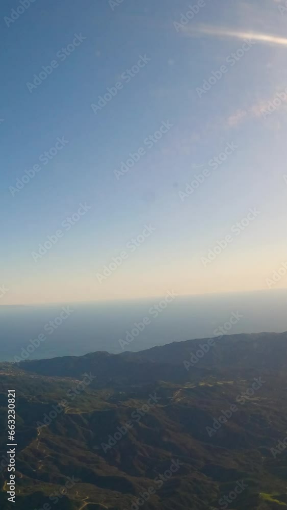 Aerial view of ocean and mountains covered in clouds. Vacation and travel concept. The plane flies over the ocean. Vertical background, vertical video background, vertical video. Aerial view of ocean and mountains covered in clouds. Vacation and travel concept. The plane flies over the ocean. Vertical background, vertical video background, vertical video.