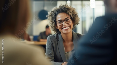 Happy African American mature middle 60s aged smiling lady boss manager talking to colleagues meeting in office space. Team leader portrait of company team working together in modern office. Closeup