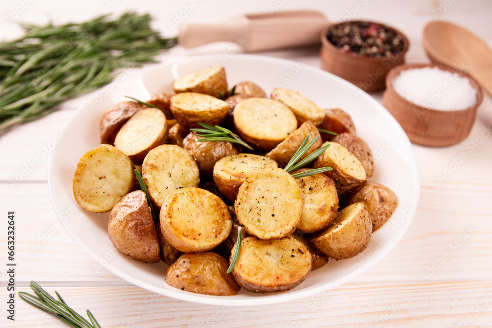 Delicious baked potatoes with rosemary on a light background