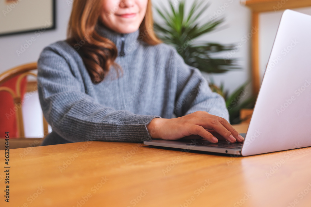 Closeup image of a woman working on laptop computer on wooden table at home