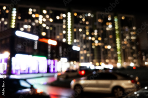 Fototapeta Naklejka Na Ścianę i Meble -  Blurred background. Night city. Blurred silhouette of buildings, bokeh spots of glowing lanterns. Blurred view of city street.Bokeh effect. Defocused night street with bokeh blur of street lights