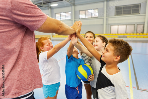 Happy students giving high five to coach in gym class photo