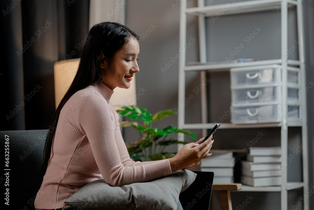 Asian woman is in the living room and uses social media on a smartphone. Female company employee on vacation. Using vacation time and free time to relax at home. Weekend vacation day doing activities. Asian woman is in the living room and uses social media on a smartphone. Female company employee on vacation. Using vacation time and free time to relax at home. Weekend vacation day doing activities.