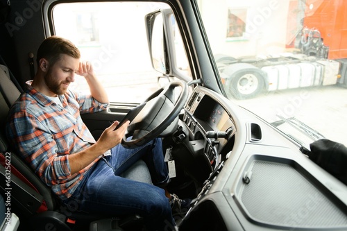 Man truck driver sitting behind wheel of car and holding digital tablet in his hands © Serhii
