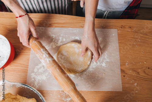 Mom and son are preparing dough for cookies at a wooden table in the kitchen. Cooking desserts at home. Joint activities with children. Top view