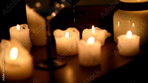 camera moves away from wine glasses and burning candles in the dark. Dinner, celebration, romantic evening.