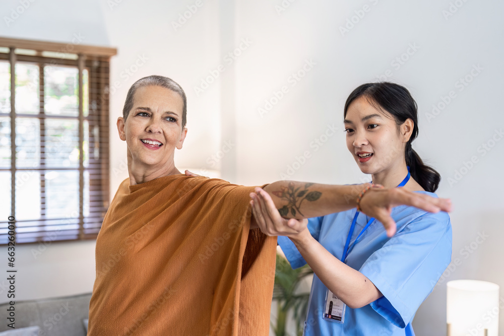 Fototapeta premium Asian female doctor advice elderly patient to physiotherapist to exercise at home