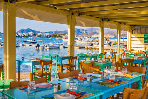 Tables and chairs in typical Greek taverna restaurant in Pollonia port, Milos island, Cyclades, Greece photo