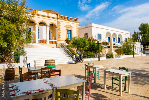 Taverna chairs with tables on square with typical Greek architecture in Plaka village, Milos island, Cyclades, Greece