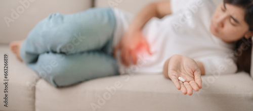 woman hand holding and eating medicine painkiller pill on the sofa at home, for stomach ache, Diarrhea Pain from food poisoning, Endometriosis, Hysterectomy and Menstrual