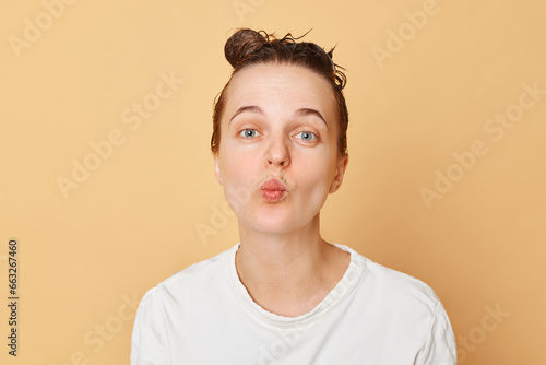 Positive funny woman washes hair applies shampoo taking shower isolated over beige background posing with purse lips having fun while doing hygiene procedures in bathroom.