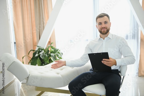 Friendly middle eastern male psychologist smiling at camera during therapy session, working in clinic, free space. Happy psychotherapist posing at office.