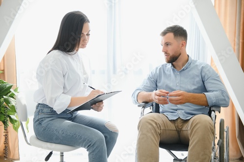 Young disabled man talking to female psychologist at home