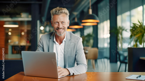 A businessman is smiling at his laptop in the office