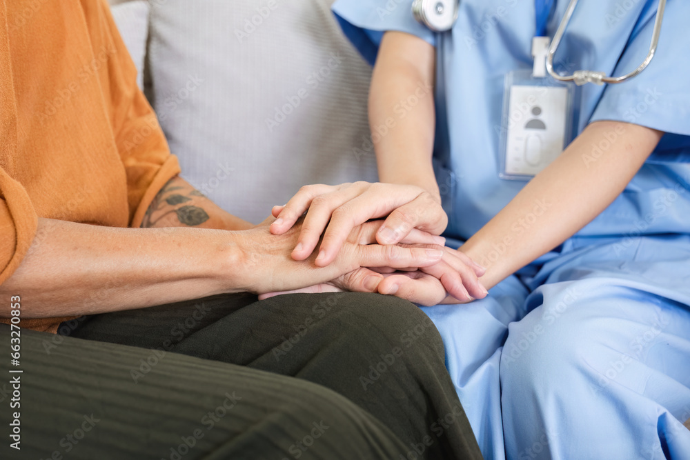 Up close, an elderly female patient holds hands with a nurse who comes to take care of her and help to encourage each other. Up close, an elderly female patient holds hands with a nurse who comes to take care of her and help to encourage each other.
