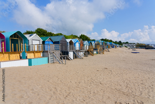 Beach huts of all shapes and sizes line the back of Abersoch beach on a bright summer day.