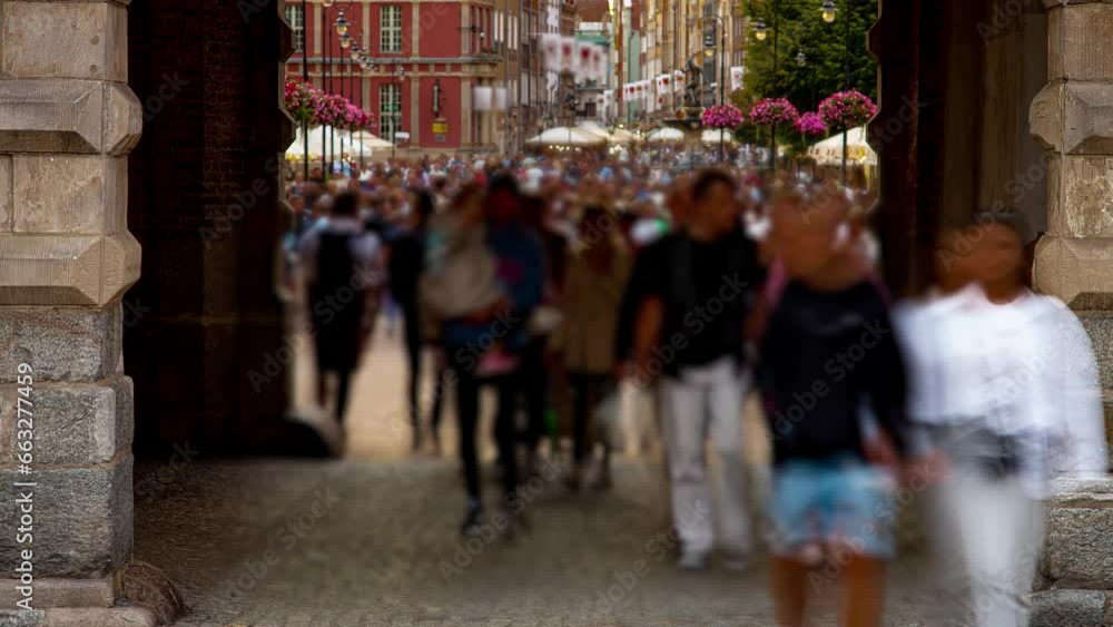 Defocused and motion blurred time lapse of crowds of people walking on busy shopping street through vintage arch of building. Vacations and traveling, tourism and tourists concept Defocused and motion blurred time lapse of crowds of people walking on busy shopping street through vintage arch of building. Vacations and traveling, tourism and tourists concept