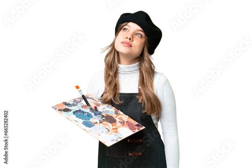 Young artist girl holding a palette over isolated chroma key background thinking an idea while looking up