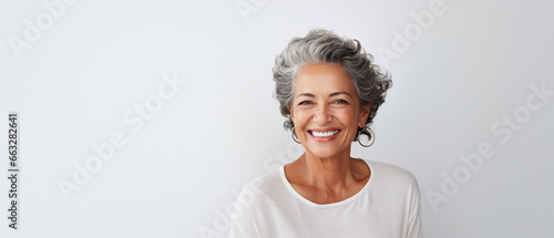 Portrait of a happy smiling beautiful aging mature woman with smooth healthy face skin on white background with empty copy space photo