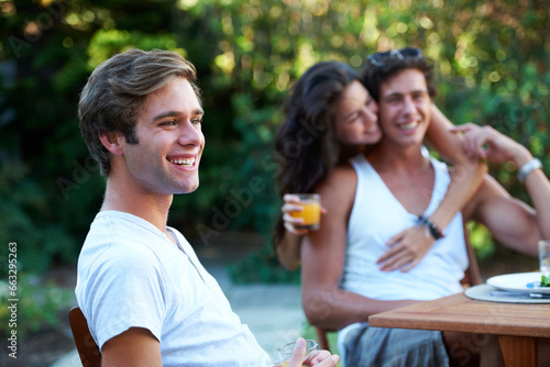 Young man, laughing and friends in a backyard at home with bbq and happy event by a table. Group, teenager and lunch with people together in a summer in a garden with a smile and food for outdoor