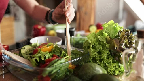 girl mixing fresh healthy vegetable salad in the bowl on the kitchen table, homemade cooking healthy food