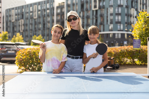 Family playing table tennis in the summer outdoors photo
