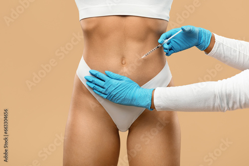 Beautician Doctor Wearing Gloves Making Beauty Injection To Female Patient Belly © Prostock-studio