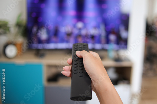 Close up hand holding television and audio remote control. 