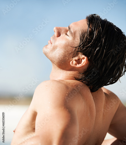Outdoor, sunshine and man with vacation, beach and tan with break, getaway and weekend trip. Person, calm and guy with seaside holiday, sunlight and relax with basking, wet and summer with freedom