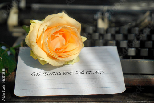 Religious inspirational quote - God  removes and God replaces. Text message with yellow rose flower on white paper on black old typewriter. Faith and believe in God concept.