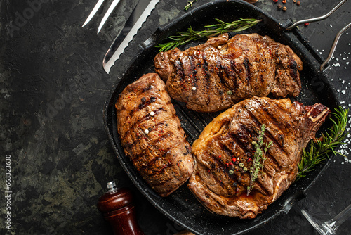 three beef steaks with grilled spices on a stone background. Restaurant menu, dieting, cookbook recipe top view.