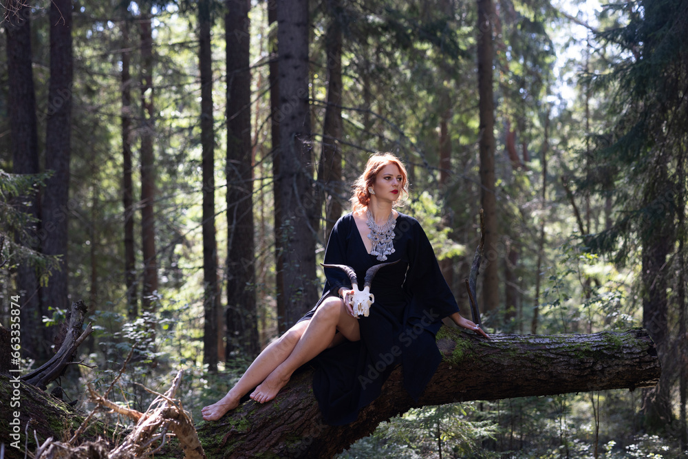 Fototapeta premium Red-haired sorceress resting in the forest on a log