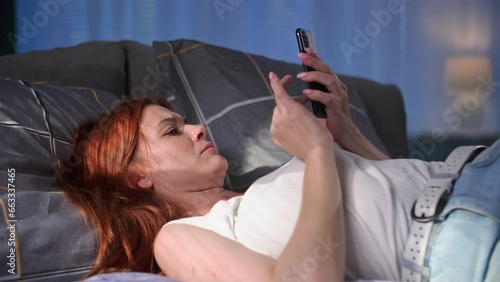 Wallpaper Mural cute young woman using mobile phone and reading news on internet while lying on sofa at home Torontodigital.ca