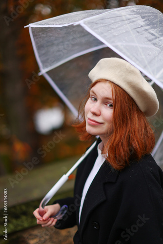 Girl rain umbrella. Happy girl portrait wearing a black coat with transparent umbrella outdoors on rainy day in park. 