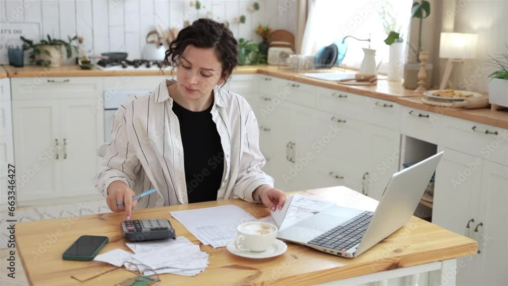 Focused caucasian woman working at home in the kitchen with financial papers, counting on a calculator, paying bills, planning a budget to find a way to save money. Self-employed accounting Focused caucasian woman working at home in the kitchen with financial papers, counting on a calculator, paying bills, planning a budget to find a way to save money. Self-employed accounting