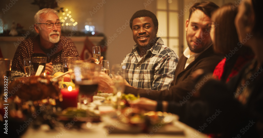 Portrait of a Handsome Young African Man Proposing a Toast at a Christmas Dinner Table. Family and Friends Sharing Meals, Raising Glasses with Champagne, Toasting, Celebrating a Winter Holiday